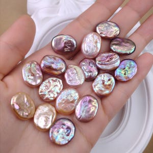 May include: A collection of small, oval-shaped, iridescent pearls in various shades of pink, purple, and gold. Each pearl features a unique, textured surface with a high-gloss finish, displaying a multi-coloured lustre that shifts in the light.
