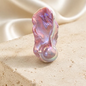 May include: A single baroque pearl with an irregular, organic shape and a lustrous, iridescent surface. The pearl displays a spectrum of soft pink, lavender, and metallic silver tones, reflecting light with a high-gloss, pearlescent finish.