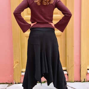 Pu&ograve; includere: Una gonna nera asimmetrica con un designo lungo e fluido. La gonna &egrave; realizzata in un tessuto morbido e confortevole e ha una vestibilit&agrave; rilassata.