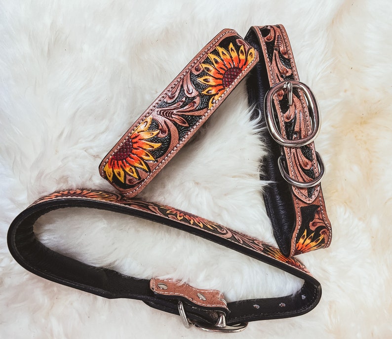 May include: Two leather dog collars with a sunflower design. One collar is black with a sunflower pattern, and the other is brown with a sunflower pattern.