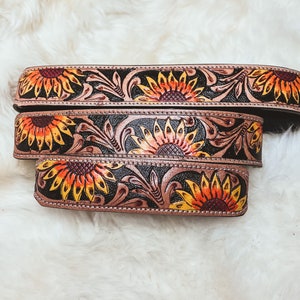 May include: Three leather belts with a sunflower design. The belts are brown with black accents and feature a floral pattern.