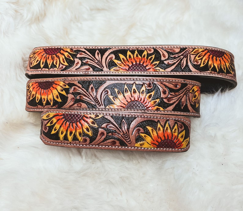 May include: Three leather belts with a sunflower design. The belts are brown with black accents and feature a floral pattern.