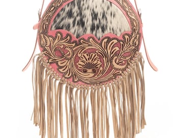 May include: A pink round leather bag with a fringe trim and a floral design. The bag has a cowhide patch in the center.