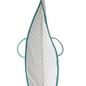 Puede incluir: Una bolsa de mano de color turquesa con forro blanco y un patr&oacute;n repetitivo de peque&ntilde;os c&iacute;rculos. La bolsa tiene dos asas.