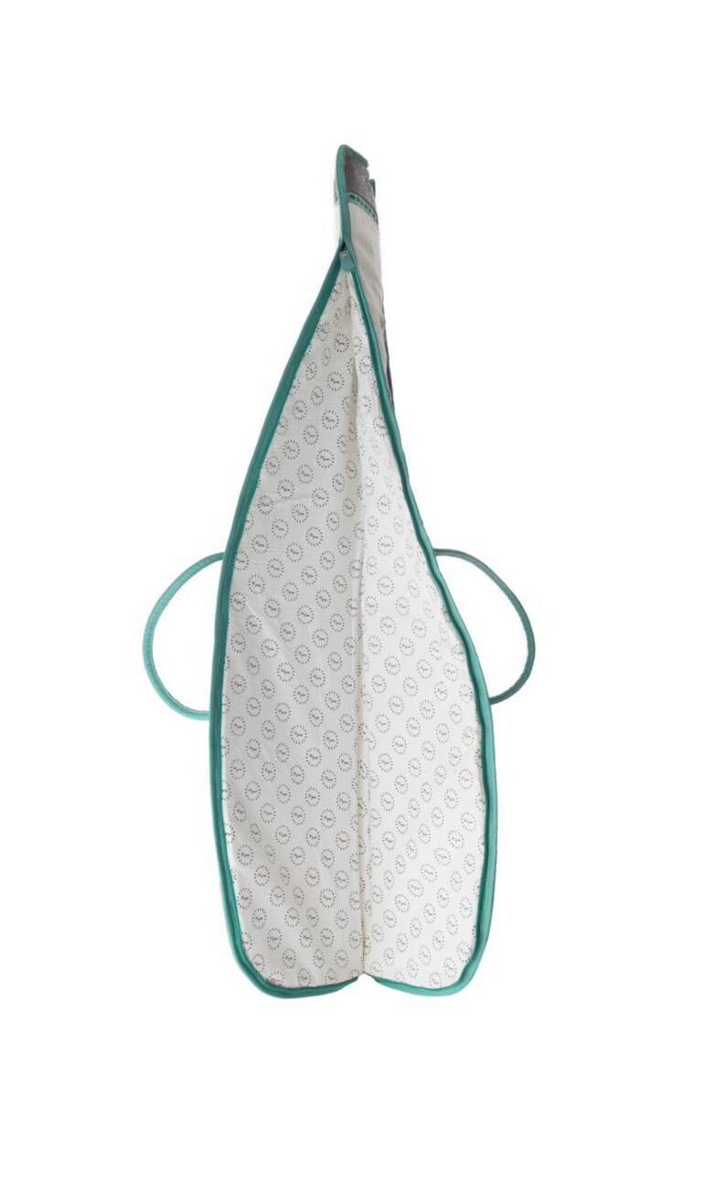 Puede incluir: Una bolsa de mano de color turquesa con forro blanco y un patr&oacute;n repetitivo de peque&ntilde;os c&iacute;rculos. La bolsa tiene dos asas.
