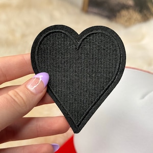 May include: Black felt heart-shaped patch. The patch is about 4 inches wide and 4 inches tall.