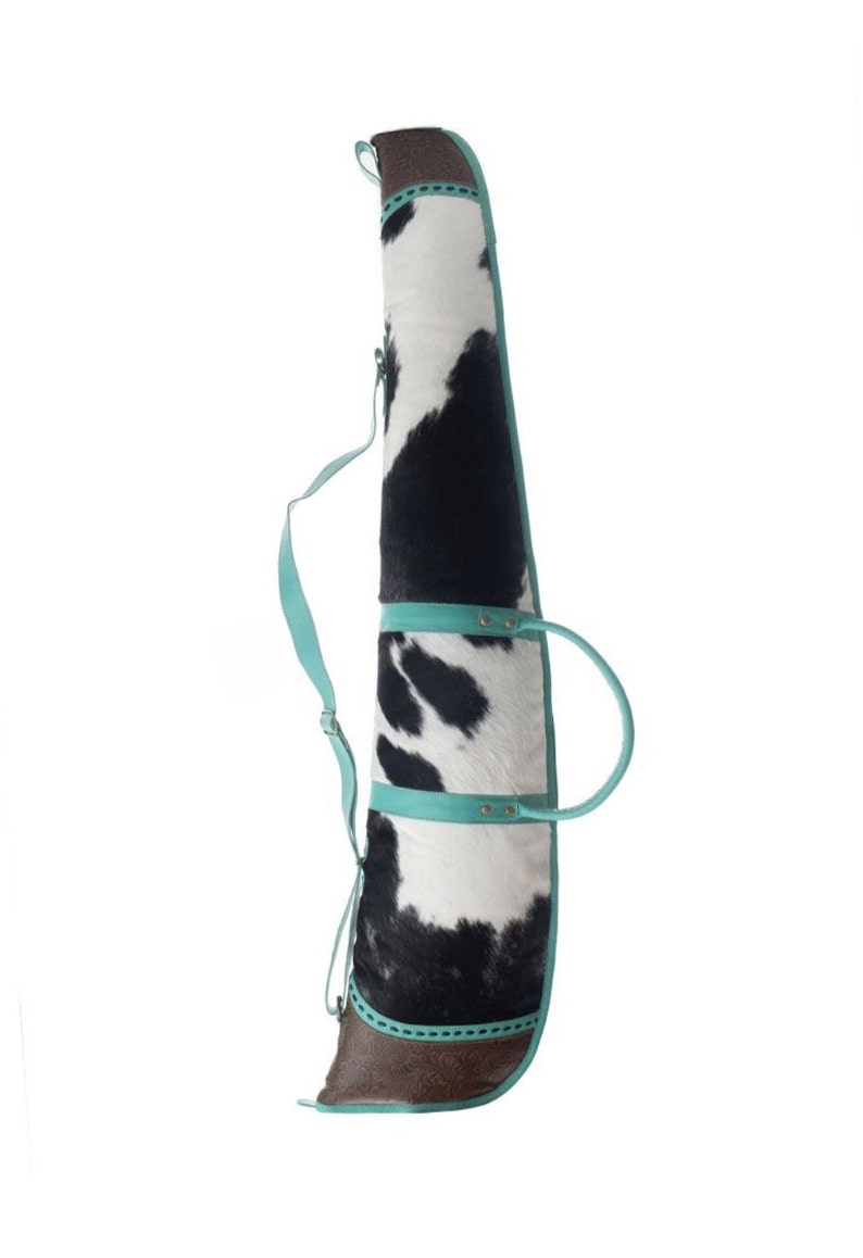 Puede incluir: Una funda para rifle de piel de vaca en blanco y negro con detalles en piel turquesa y una correa para el hombro.