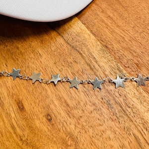 May include: A silver chain necklace with star-shaped charms. The chain is delicate and the stars are evenly spaced.