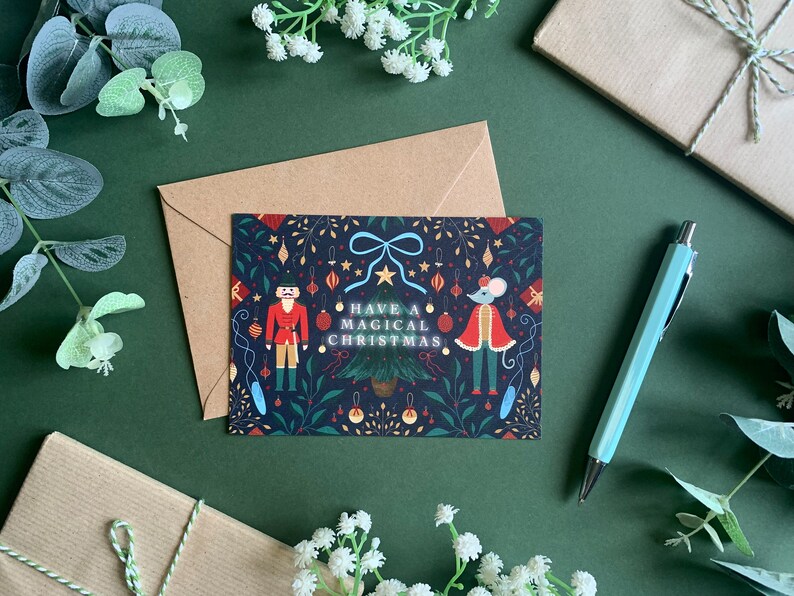 May include: A Christmas card with a dark blue background featuring a nutcracker and a mouse in festive attire. The card has a white border and the text "Have a Magical Christmas" in white letters.