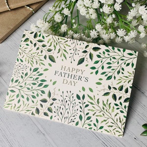 May include: A white card with a green leafy pattern and the text "Happy Father's Day" in gold lettering.