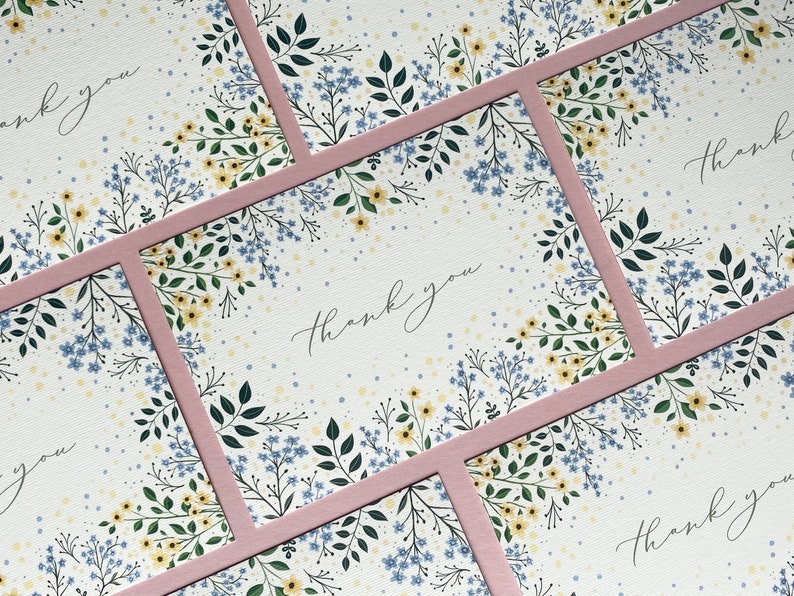 Puede incluir: Conjunto de cuatro tarjetas de agradecimiento con un dise&ntilde;o floral. Las tarjetas tienen un borde rosa y est&aacute;n impresas en papel blanco. El texto "Gracias" est&aacute; escrito en cursiva negra.