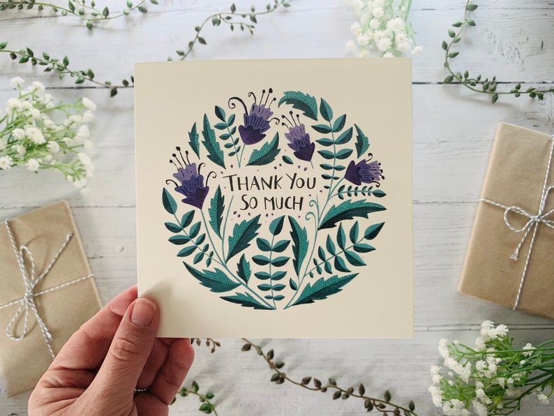 May include: A thank you card with a circular design featuring purple flowers and green leaves. The text "Thank You So Much" is written in the centre of the card.