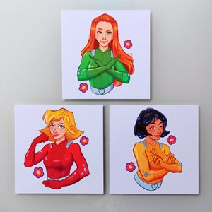 May include: Three illustrated cards featuring characters from the cartoon series 'Totally Spies!' Each card features a different character: Clover in green, Sam in red, and Alex in yellow. The characters are depicted in their signature poses, with their signature colors and accessories.