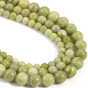 May include: A strand of light green jade beads, with a variety of sizes and shapes. The beads are strung on a clear thread and are arranged in a random pattern.