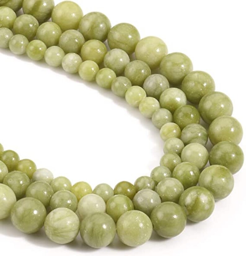 May include: A strand of light green jade beads, with a variety of sizes and shapes. The beads are strung on a clear thread and are arranged in a random pattern.