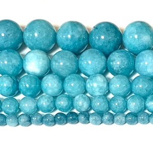 May include: A strand of light blue aquamarine beads in various sizes. The beads are round and smooth, with a slightly cloudy appearance.