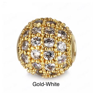 May include: A gold-toned round bead with a pave setting of clear cubic zirconia stones. The bead is approximately 10mm in diameter.  Gold-White.