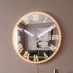 May include: A large circular wall clock with a mirrored surface and illuminated Roman numerals. The clock features a glowing LED border and two central hands that are also lit. A white power cord hangs from the bottom of the clock down to the floor.