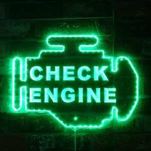 Pode incluir: Um sinal de néon verde em forma de motor de carro com as palavras "CHECK ENGINE" em branco.