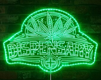 Pode incluir: Placa de néon verde com um design de folha de maconha e a palavra "DISPENSARY" em uma fonte decorativa. A placa tem um cordão branco pendurado na parte inferior.