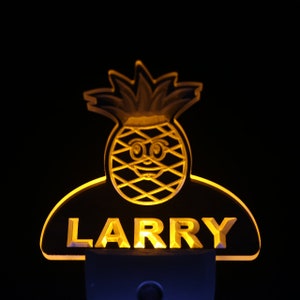 May include: A yellow pineapple-shaped night light with a smiling face and the name "LARRY" written below it.