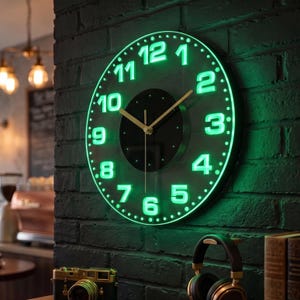 Puede incluir: Un reloj de pared redondo con esfera negra y números verdes brillantes del 1 al 12. El reloj cuenta con manecillas finas de color dorado para las horas, minutos y segundos, centradas sobre un fondo circular negro, montado en una pared de ladrillo.