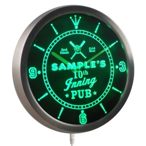 May include: Green neon clock with a black background and a silver frame. The clock face features the text "SAMPLE'S 10th Inning PUB" with baseball bats and a baseball. The clock has a green neon glow.