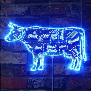 May include: Blue neon sign shaped like a cow with different cuts of meat labeled. The sign includes the labels "Chuck Rib", "Short Loin", "Short Plate", "Round", and "Shank".