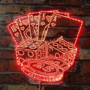 Op de afbeelding: Rood neonbord met speelkaarten en dobbelstenen. De kaarten zijn in een waaier gerangschikt met de aas van schoppen zichtbaar. De dobbelstenen zijn op elkaar gestapeld met een chip in het midden.