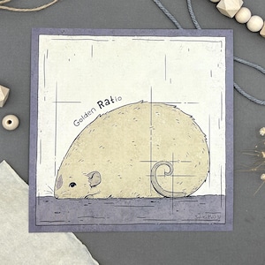 Puede incluir: Impresión artística cuadrada con una ilustración estilizada de un roedor beige claro con una cola enroscada. El texto "Golden Ratio" está arqueado sobre el roedor. La impresión tiene un borde gris y está firmada "Sadie Muga".