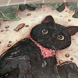 Puede incluir: Un gato negro con una pajarita de lunares rosas est&aacute; tumbado sobre una superficie marr&oacute;n claro con puntos marrones dispersos. El gato tiene ojos grandes y redondos y una expresi&oacute;n de sorpresa.