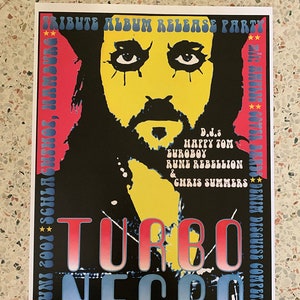 以下が含まれることがあります： 黒と白のポスターで、黄色い顔に黒い目と黒いひげがあります。ポスターは、Turbo Negroのトリビュートアルバムのリリースパーティー用です。ポスターには、「Tribute Album Release Party」、「Turbo Negro」、「V.A. Alpha Motherfuckers LP.CD」、「www.bitzcore.com」、「Artwork Adam T. 2001 for www.altamontrerecords.com」、「Präsentiert von VISIONS musikmagazin」、「D.J.s Happy Tom, Euroboy, Rune Rebellion & Chris Summers」、「mit: Amuses Cows, Bands, Denim Disguise Competition」、「SOMSOTHES#1002 INAP'C」というテキストが記載されています。