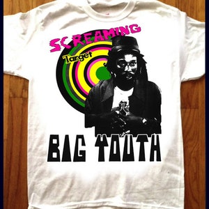 Könnte beinhalten: Weißes T-Shirt mit einem Schwarzweißbild eines Mannes mit Hut und einer grünen, gelben und pinkfarbenen Zielgrafik mit dem Text "Screaming Target" und "Big Youth" auf der Vorderseite.