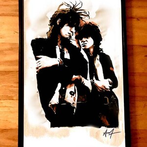 May include: A black and white watercolor painting of two men with long hair, standing close together. The painting is framed in a black frame and signed "A7" in the bottom right corner.