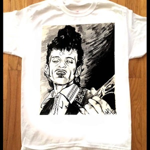 May include: A white t-shirt with a black and white illustration of a man with a guitar. The man has dark hair and is wearing a collared shirt. The illustration is in a cartoon style.
