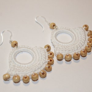 May include: White crocheted earrings with a circle design and wooden beads.