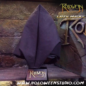 May include: A black latex mask with a pointed hood. The mask is displayed on a black stand with the text "Roloween Studio" in gold lettering. The text "Latex Masks" is visible in the background.