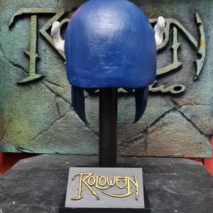 May include: Blue and white helmet with horns on a black stand with the word "Roloween" on the base.