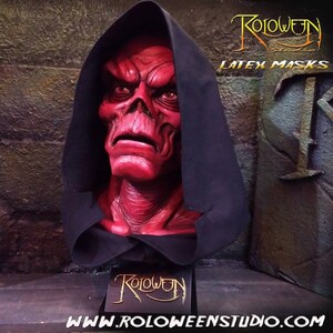May include: A red latex mask of a demon with a black hooded robe. The mask is on a display stand with the text "Roloween Studio" on it. The text "Latex Masks" is visible in the background.
