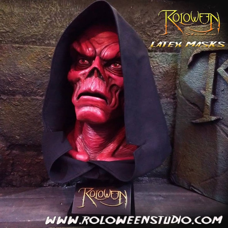 May include: A red latex mask of a demon with a black hooded robe. The mask is on a display stand with the text "Roloween Studio" on it. The text "Latex Masks" is visible in the background.
