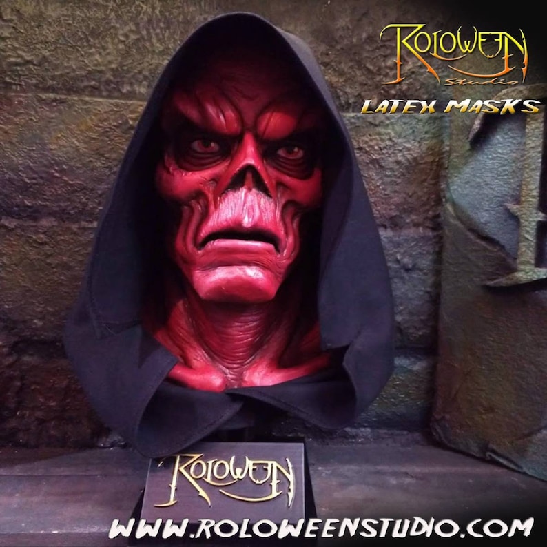 May include: A red latex mask of a demonic figure with a black hooded robe. The mask has a detailed skull-like face with a menacing expression. The text "Roloween Studio Latex Masks" is visible in the background.