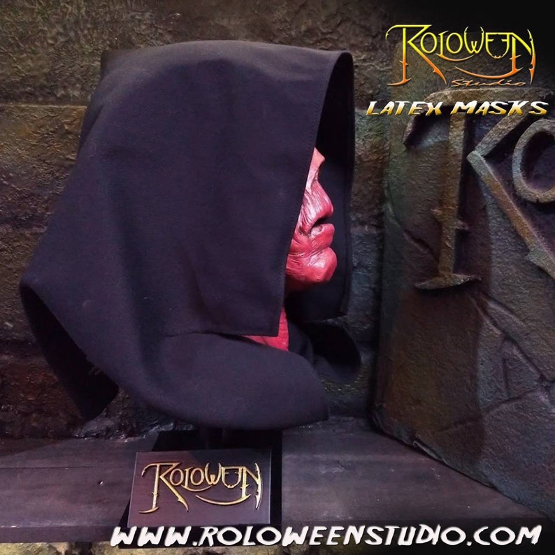 May include: A red latex mask with a black hooded robe. The mask has a detailed, grotesque expression. The text "Roloween Studio Latex Masks" is visible in the background.