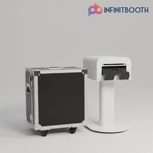 Può includere: Un fotomaton bianco con una stampante e una valigia nera su ruote. Il fotomaton ha il testo "INFINITBOOTH" nell'angolo in alto a destra.