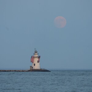 Photograph of the full Buck Moon rising over the Breakwater Lighthouse in Old Saybrook, Connecticut