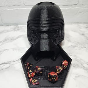 May include: Black 3D printed dice tray shaped like Kylo Ren's helmet with red and black dice inside.