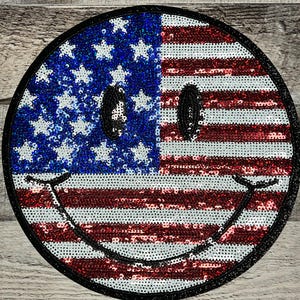 May include: A red, white, and blue American flag smiley face patch made of sequins.