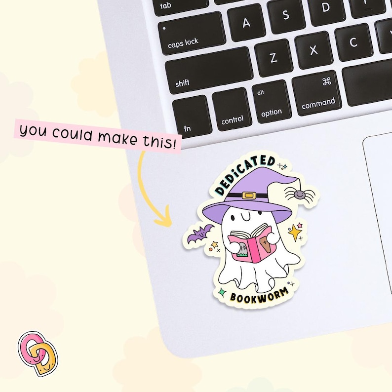 以下が含まれることがあります： 紫色の魔女の帽子をかぶってピンクの本を持っている白い幽霊。幽霊は幸せそうな顔をしていて、星とコウモリに囲まれています。幽霊の下には「DEDICATED BOOKWORM」という文字が書かれています。