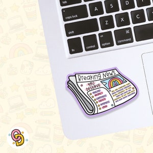 May include: A sticker of a newspaper headline that reads "Breaking News: You Deserve" with a list of positive affirmations including healing, respect, happiness, safety, kindness, and love. The sticker is on a laptop keyboard.