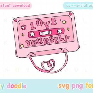 May include: Pink cassette tape with a white outline and the text "LOVE YOURSELF" in white letters with a pink heart and stars. The cassette tape has a pink cord attached to it.