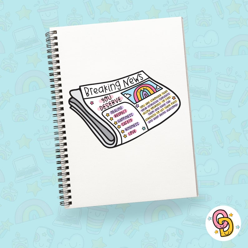 May include: A white notebook with a spiral binding features a cartoon illustration of a newspaper headline that reads "Breaking News: You Deserve." The newspaper is decorated with a rainbow and a list of positive words including healing, respect, happiness, safety, kindness, and love.